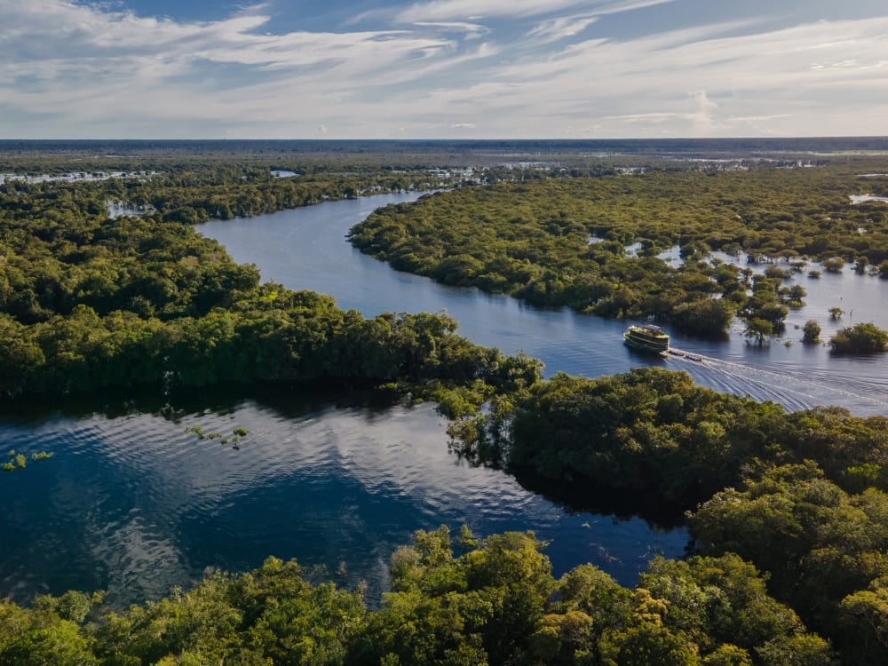 Vue aérienne d'une rivière bleue sinueuse traversant la végétation verte et dense de la forêt Amazonienne au Brésil. Vue aérienne d'une rivière bleue sinueuse traversant la végétation verte et dense de la forêt Amazonienne au Brésil.