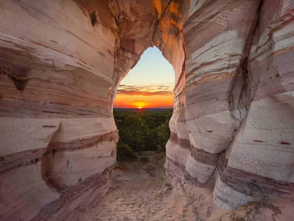 Ein strahlender Sonnenuntergang, durch eine natürliche Sandsteinwand betrachtet, der das durchweg sonnige Wetter im Norden Brasiliens hervorhebt. Ein strahlender Sonnenuntergang, durch eine natürliche Sandsteinwand betrachtet, der das durchweg sonnige Wetter im Norden Brasiliens hervorhebt.