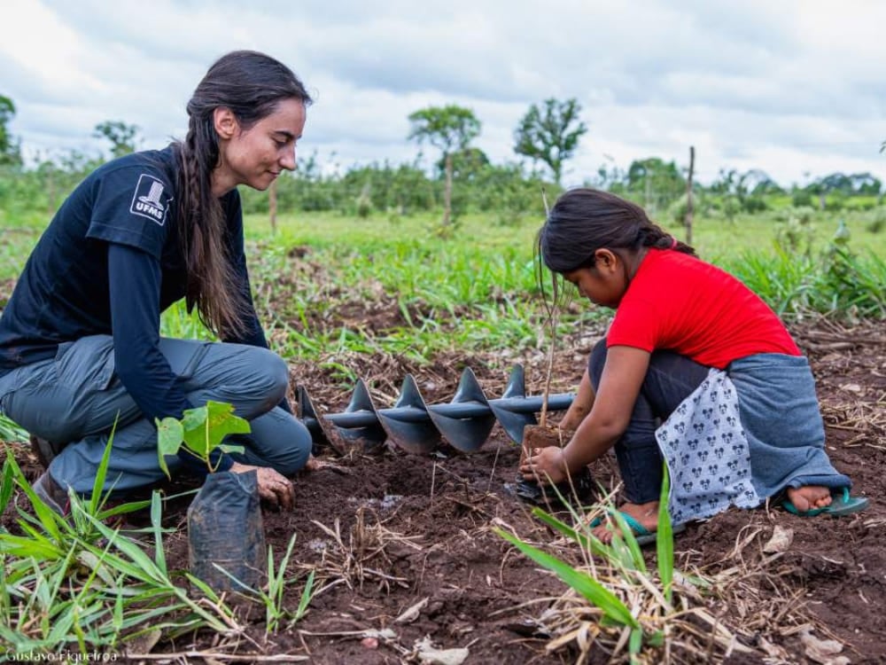 Une femme et une jeune fille agenouillées dans la terre pour planter un jeune arbre au Pantanal. Une femme et une jeune fille agenouillées dans la terre pour planter un jeune arbre au Pantanal.