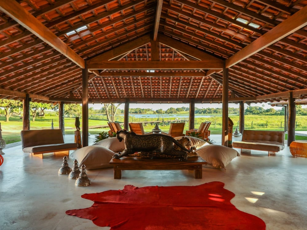 L'intérieur luxueux de l'auberge Caiman présente un plafond en bois, des espaces de repos confortables et une grande statue de jaguar. L'intérieur luxueux de l'auberge Caiman présente un plafond en bois, des espaces de repos confortables et une grande statue de jaguar.
