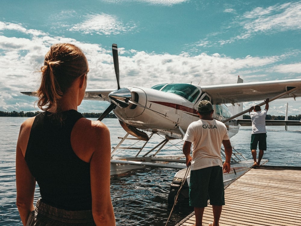 Un voyageur debout sur une jetée en bois regardant un petit hydravion amarré sur le fleuve Amazone, prêt à embarquer. Un voyageur debout sur une jetée en bois regardant un petit hydravion amarré sur le fleuve Amazone, prêt à embarquer.