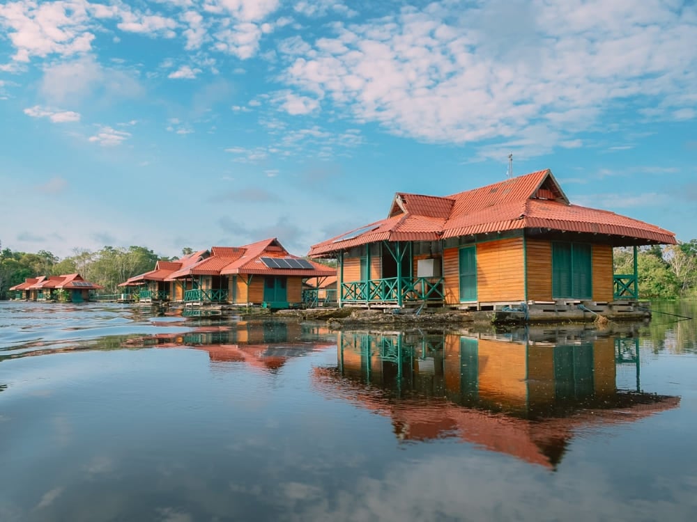 Die schwimmenden Bungalows der Uakari Lodge auf dem dunklen Flusswasser, ein einzigartiges Ziel für Ökotourismus in Brasilien. Die schwimmenden Bungalows der Uakari Lodge auf dem dunklen Flusswasser, ein einzigartiges Ziel für Ökotourismus in Brasilien.