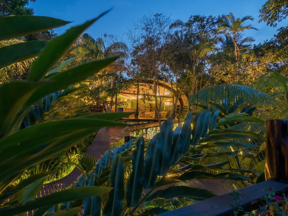 Modern wood and glass architecture of the Mirante do Gaviao hotel illuminated at night in the jungle. Modern wood and glass architecture of the Mirante do Gaviao hotel illuminated at night in the jungle.