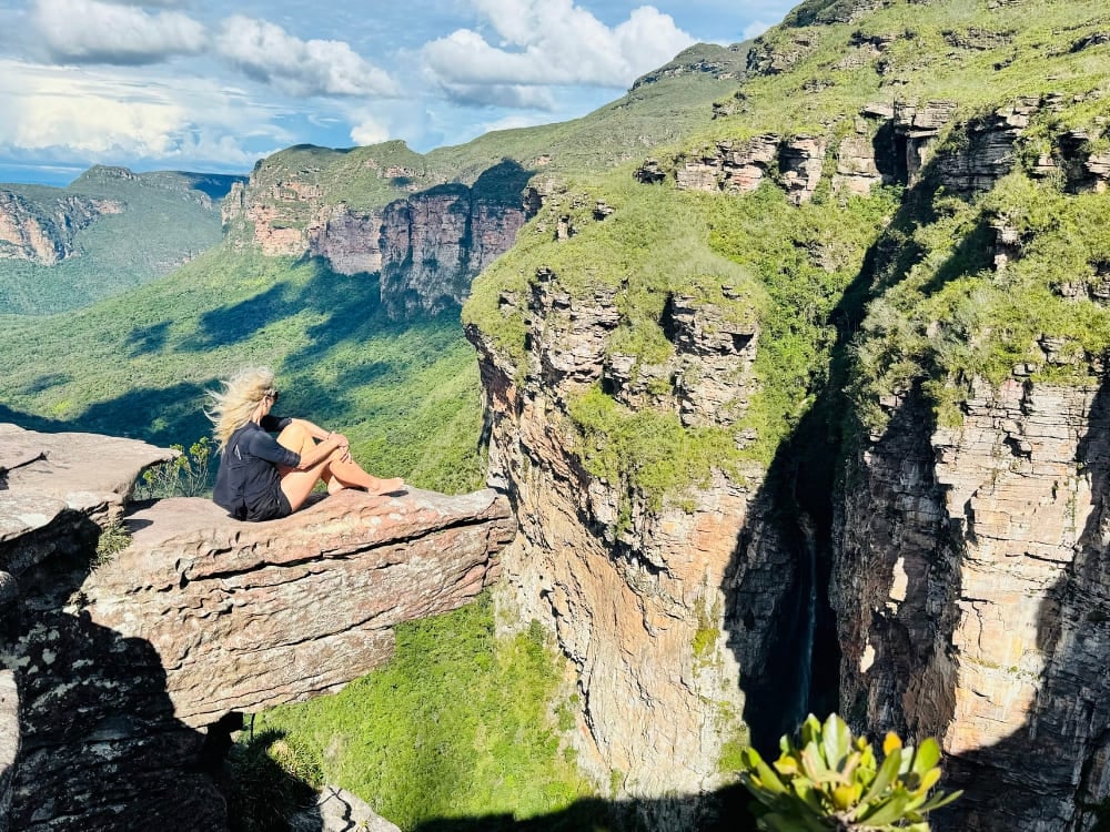 Une aventurière assise au bord d’un rocher admire les vastes paysages verdoyants de la Chapada Diamantina, au Brésil. Une aventurière assise au bord d’un rocher admire les vastes paysages verdoyants de la Chapada Diamantina, au Brésil.