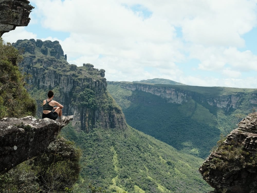 Mulher sentada na beira de um penhasco rochoso contemplando a imensidão verde dos planaltos e vales da Chapada Diamantina. Amazônia (AM) Mulher sentada na beira de um penhasco rochoso contemplando a imensidão verde dos planaltos e vales da Chapada Diamantina.Amazônia (AM)