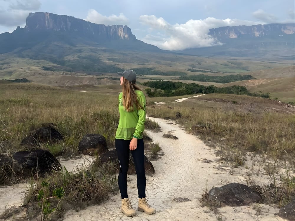 Une femme écotouriste sur un sentier de terre, avec la merveille naturelle du Mont Roraima en arrière-plan. Une femme écotouriste sur un sentier de terre, avec la merveille naturelle du Mont Roraima en arrière-plan.