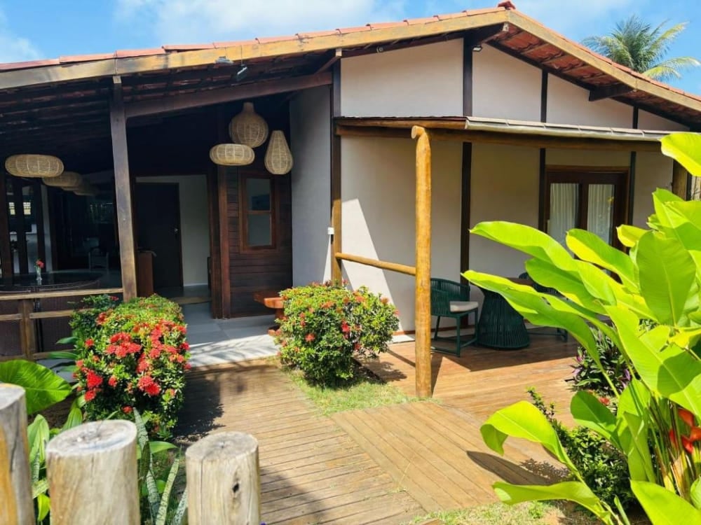 Extérieur d'une charmante maison d'hôtes comprenant un porche couvert, des piliers en bois et un jardin tropical verdoyant à Fernando de Noronha. Extérieur d'une charmante maison d'hôtes comprenant un porche couvert, des piliers en bois et un jardin tropical verdoyant à Fernando de Noronha.