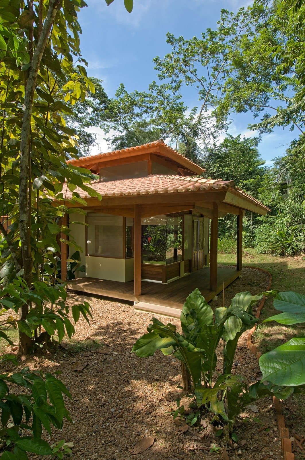 Your own patch of forest, with a roof and a proper deck. Photo: Luis Gomes A compact wooden bungalow with a terracotta-tiled pagoda-style roof and open verandah, nestled among tall tropical trees and lush understorey plants at a jungle lodge