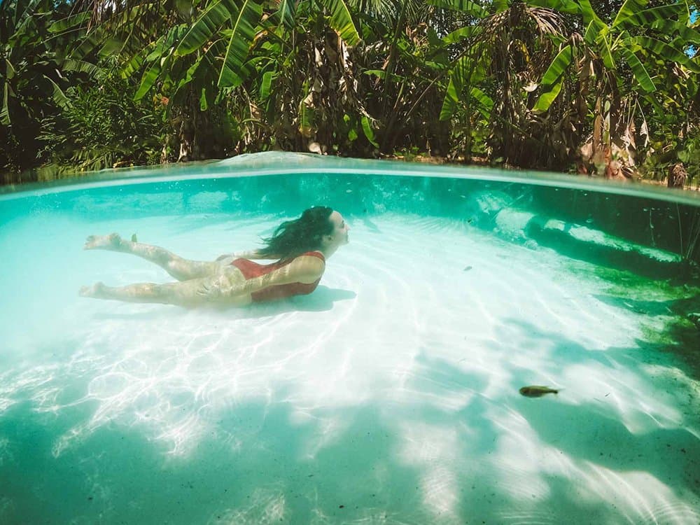 Sink? Not possible. Float like you own the place. Woman in a red bikini floating underwater in a crystal-clear fervedouro natural spring surrounded by lush tropical vegetation, a highlight of Jalapão trekking