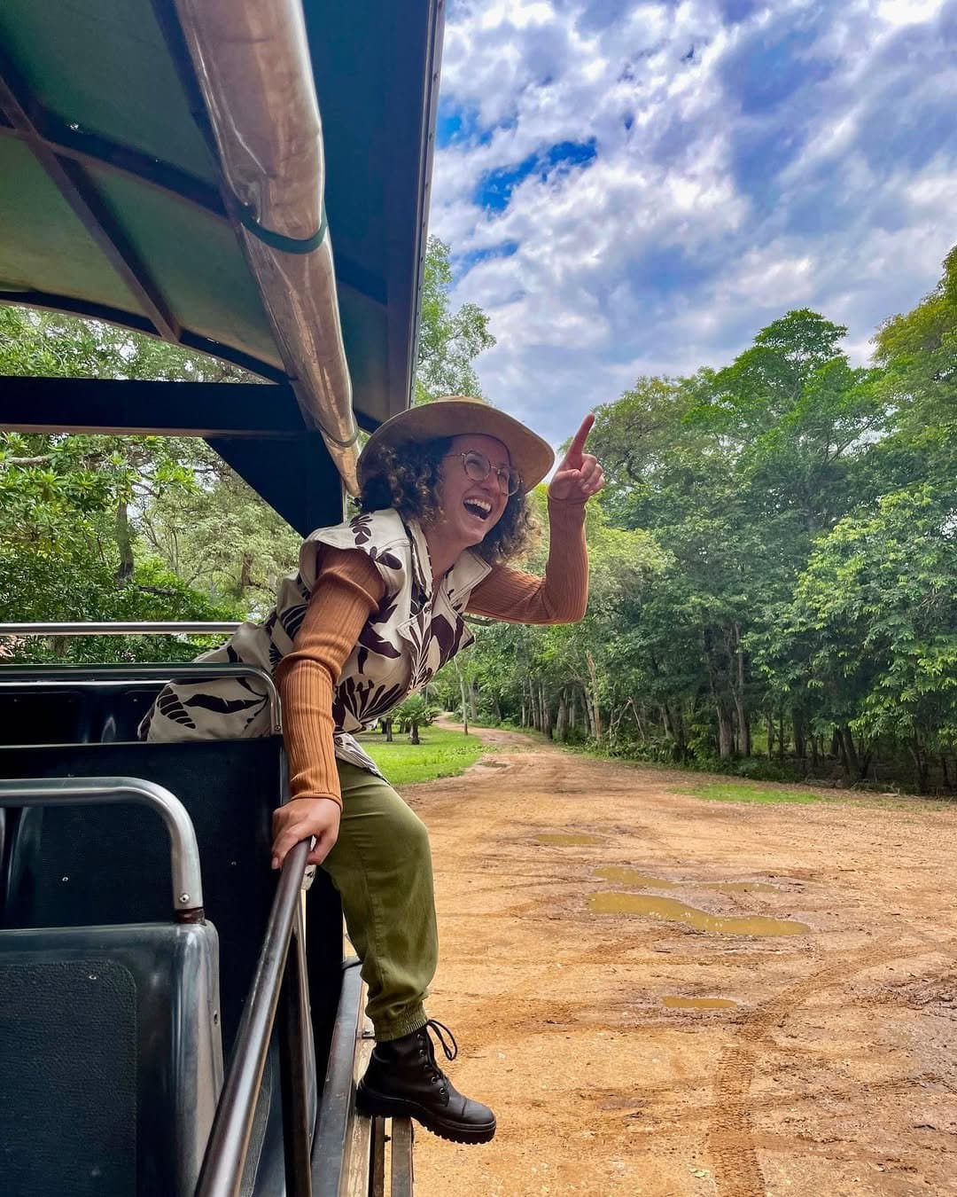Un doigt levé, et tout le monde scrute la cime des arbres. Une femme hilare coiffée d'un chapeau de brousse se penche hors d'un 4x4 ouvert lors d'un safari dans le sud du Pantanal, pointant le ciel du doigt sur une piste boueuse bordée d'arbres denses.