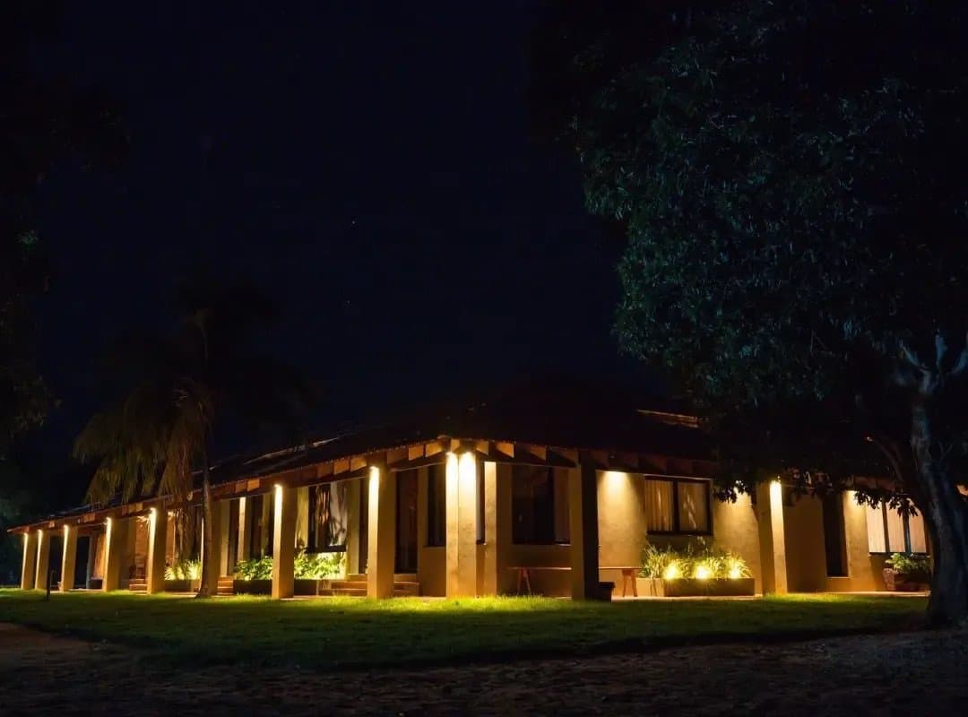Ce genre d'endroit que l'on apprécie encore plus après une journée entière sur le terrain. Un lodge de style ranch illuminé d'une lumière dorée chaleureuse la nuit, entouré de pelouses et d'arbres lors d'un safari dans le sud du Pantanal