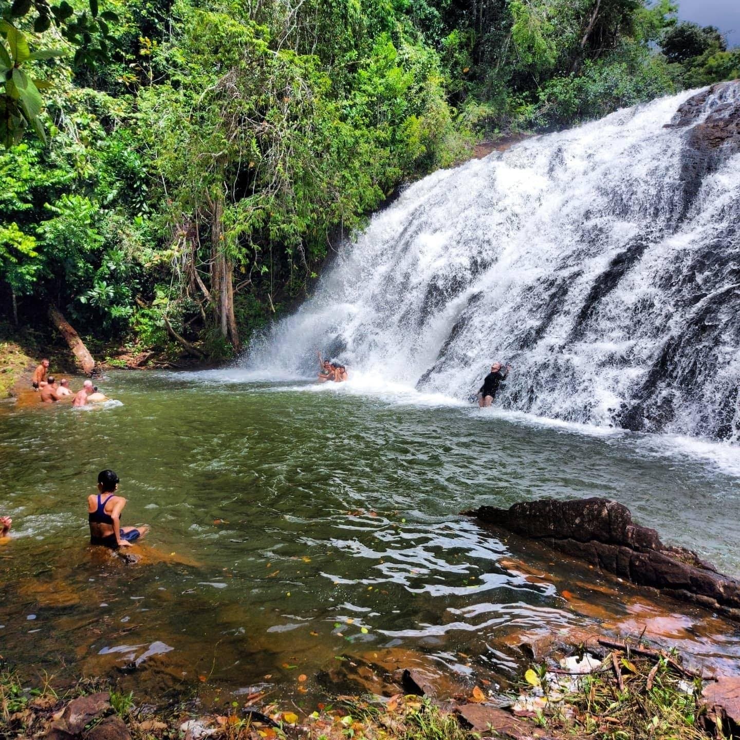 Bicicletas paradas, tênis tirado, todo mundo na água. Tem prêmio que só vem assim. Viajantes nadam no poço natural da Cachoeira Milagrosa, uma queda d'água larga sobre rochas escuras em meio à Mata Atlântica, parada refrescante no roteiro de cicloturismo na Bahia
