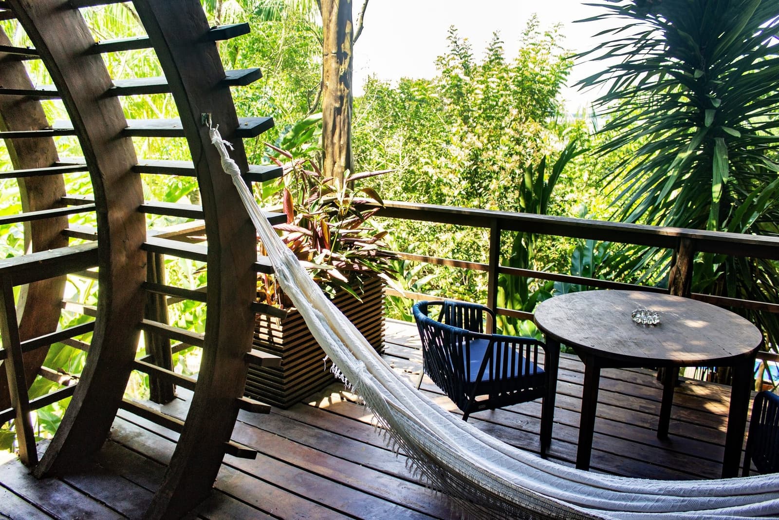 Un hamac, une table pour le café, et la forêt qui s'occupe du reste. Un hamac blanc tendu sur une terrasse en bois courbée au Mirante do Gavião, avec une table ronde, un fauteuil en rotin et la canopée amazonienne en arrière-plan