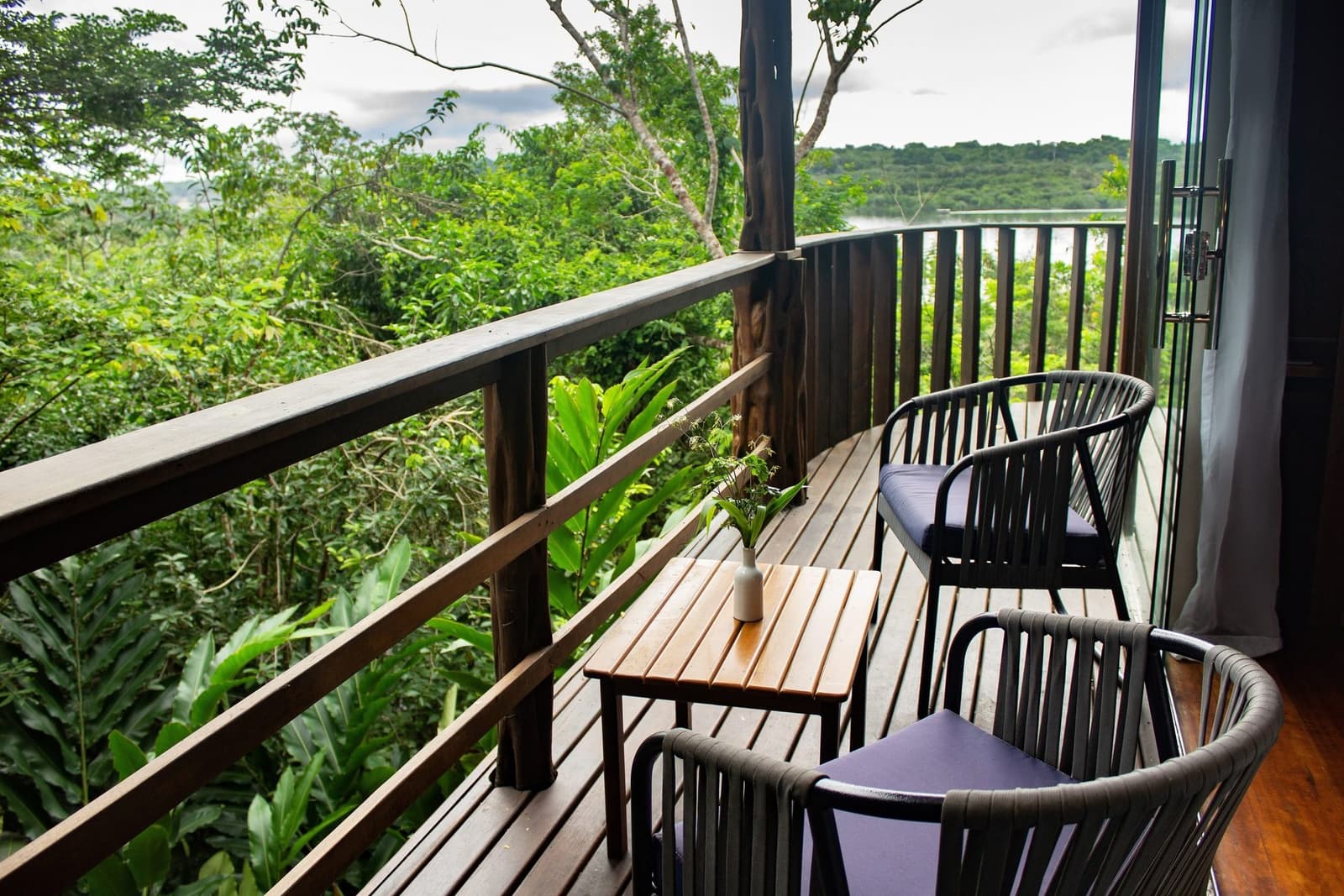 Le genre de terrasse où on oublie de rentrer. Balcon en bois courbé au Mirante do Gavião équipé de deux fauteuils rembourrés et d'une petite table en lattes donnant sur une dense canopée de forêt tropicale et une rivière entrevue au loin
