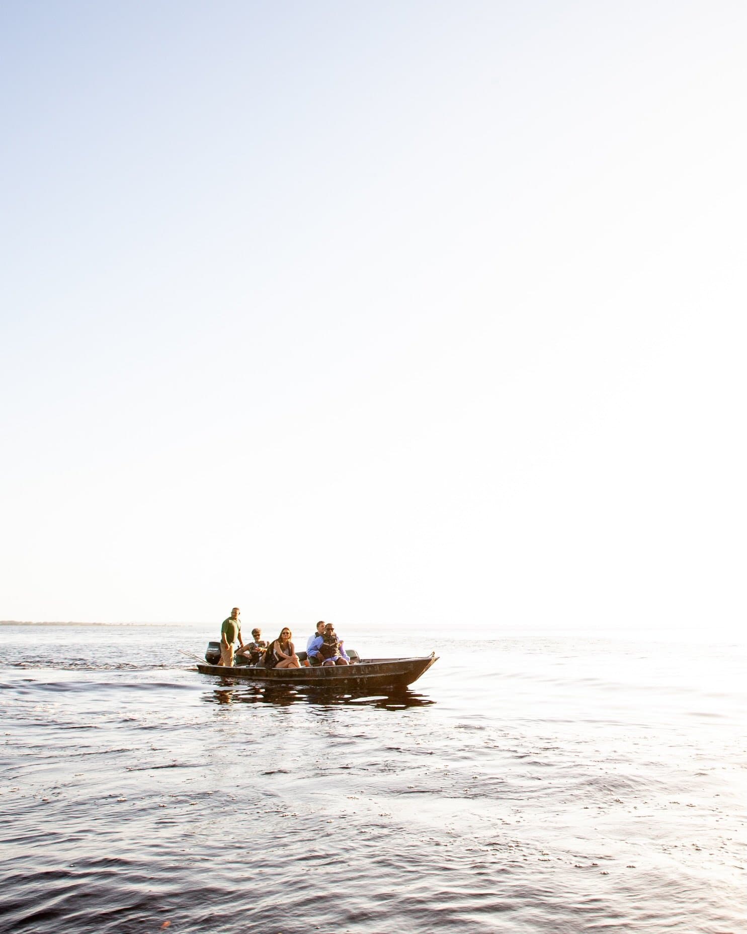 Le fleuve avance, le groupe se laisse porter. Un petit bateau à moteur transportant cinq passagers glisse sur les eaux calmes et sombres du Rio Negro lors d'une excursion en bateau à Mirante do Gavião, sous un ciel pâle et brumeux