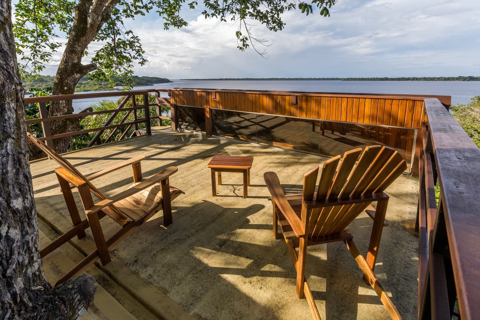 Un siège, un fleuve, et rien d'urgent à faire. Deux fauteuils Adirondack en bois et une petite table sur une terrasse ouverte du Mirante do Gavião, face à un large fleuve aux eaux sombres entouré de forêt amazonienne