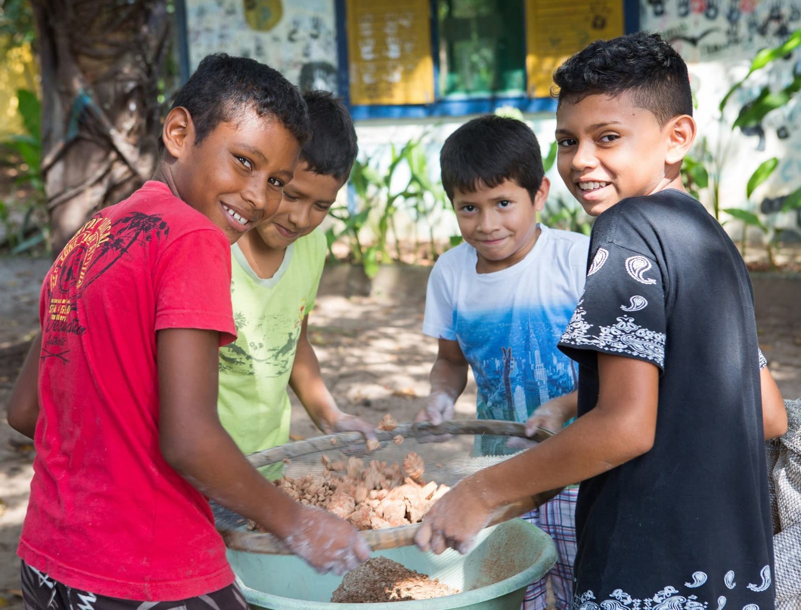 Quand on met la main à la pâte, on ne compte plus les sourires. Quatre garçons souriants trient et tamisent ensemble des aliments récoltés dans un grand bassin à l'extérieur, au sein d'une communauté riveraine près de Mirante do Gavião