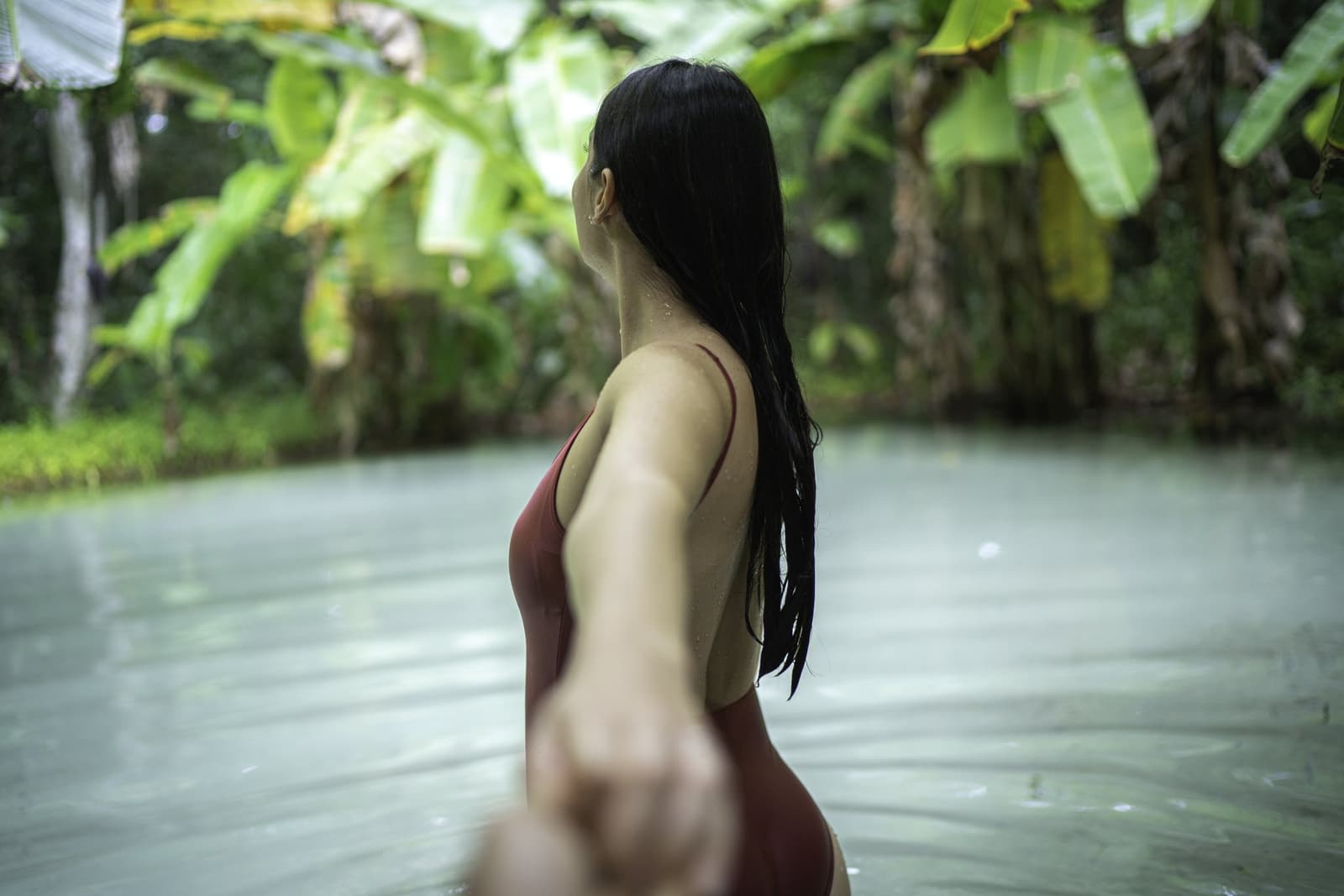 L'eau fraîche vous porte — impossible de couler. Photo: FG Trade Une femme en maillot de bain rouge avance dans les eaux calmes et d'un vert laiteux d'un fervedouro lors d'un circuit de 4 jours au Jalapão, entourée d'une végétation tropicale luxuriante
