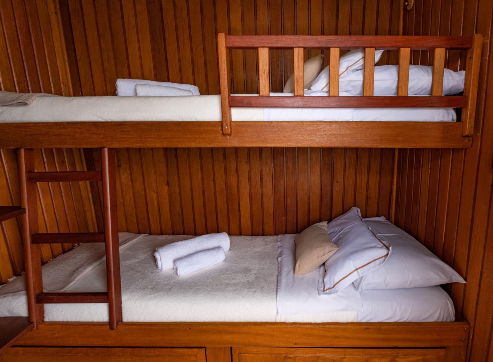 Petit espace, grand confort, la vie sur le fleuve a son propre tempo. Lits superposés en bois soigneusement faits avec du linge blanc, des serviettes roulées et des oreillers gris dans une cabine lambrissée à bord d'une croisière Amazone depuis Alter do Chão