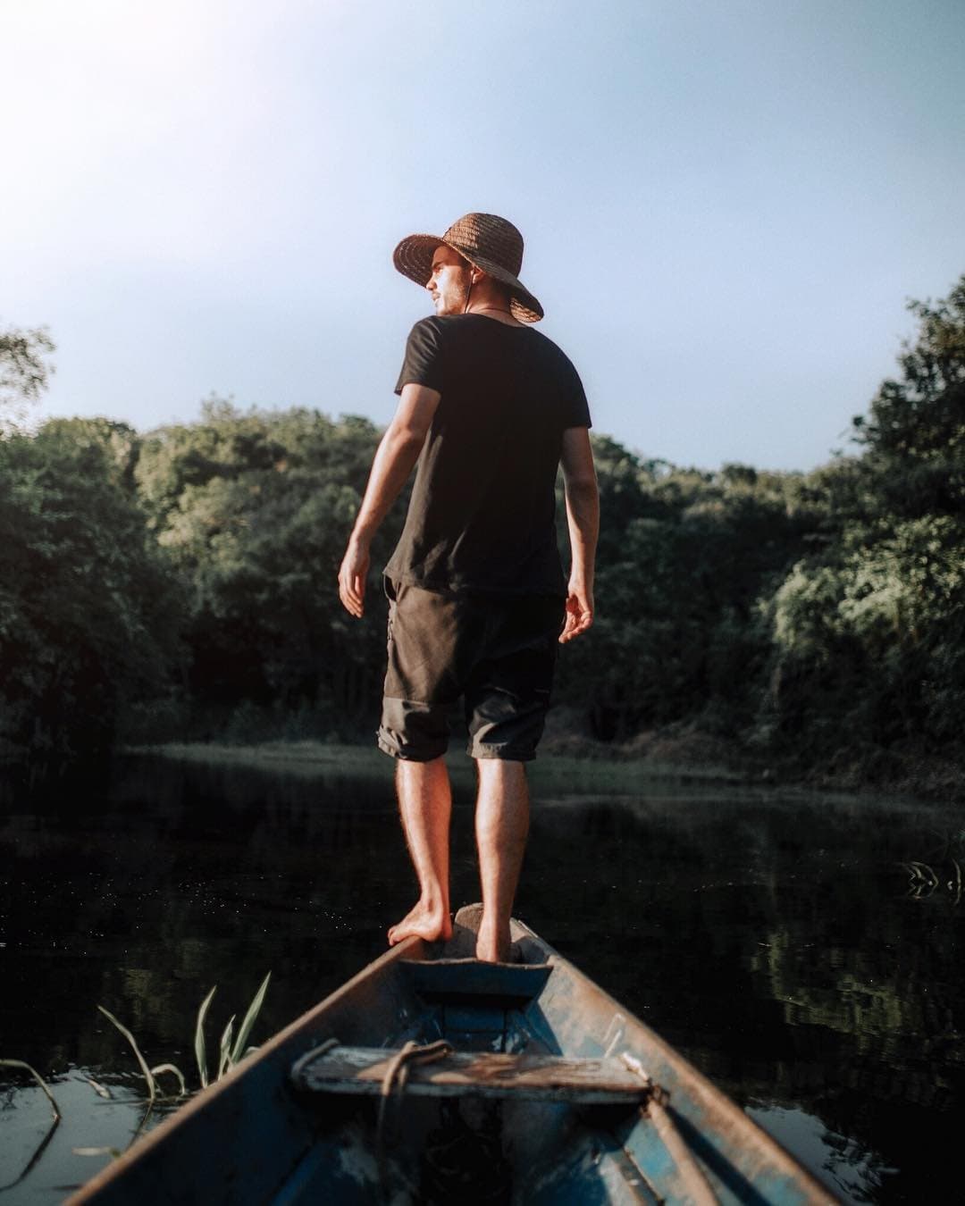 Kein Zeitplan, kein Schuhwerk, nur der Fluss und die nächste Biegung. Ein barfüßiger Mann mit Strohhut steht auf dem Bug eines alten Holzkanus und blickt auf einen ruhigen, dunklen Fluss, gesäumt von dichtem grünem Dschungel