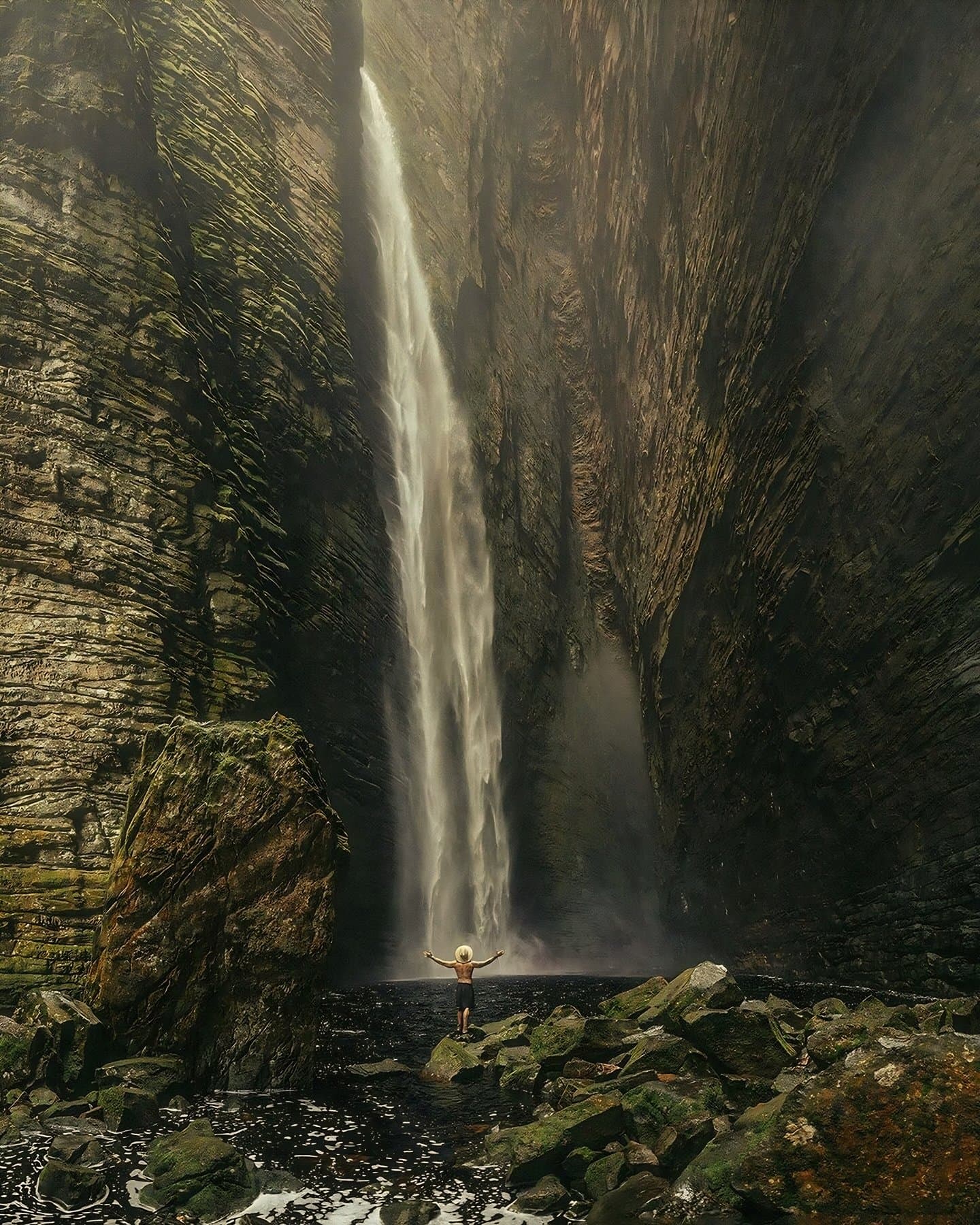 Bras grands ouverts, le canyon relativise tout le reste. Un randonneur solitaire les bras levés devant la cascade Fumacinha qui plonge dans un canyon de grès étroit lors d'une randonnée dans la Chapada Diamantina