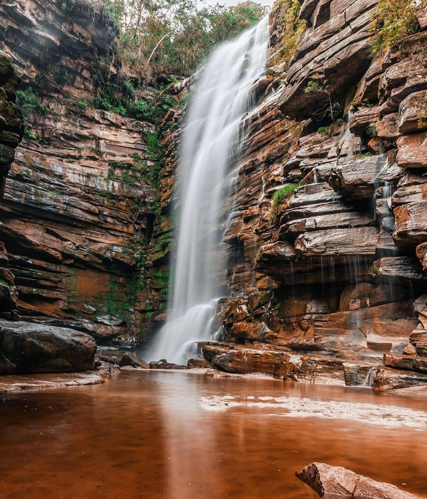 Rust-red water, silken falls — sandstone carved by centuries of flow. Photo 1