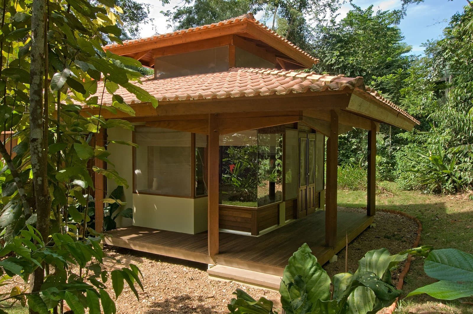 Slapen in het bos, met alle gemak om je heen. Een houten bungalow met terracotta dakpannen en een omlopend hardhouten terras bij Cristalino Jungle Lodge, omgeven door weelderig tropisch groen