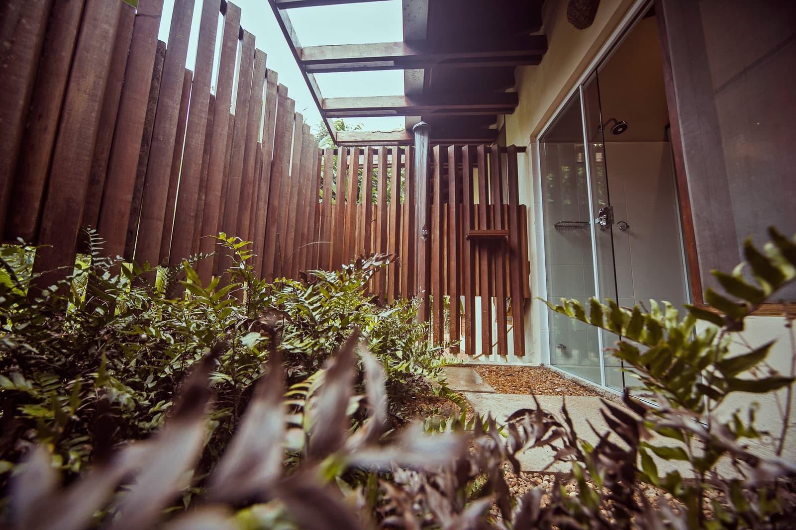 Douchen met het oerwoud op een armlengte afstand. Een privé buitendouche bij Cristalino Jungle Lodge, omgeven door verticale hardhouten latten en weelderig tropisch groen onder een open hemel