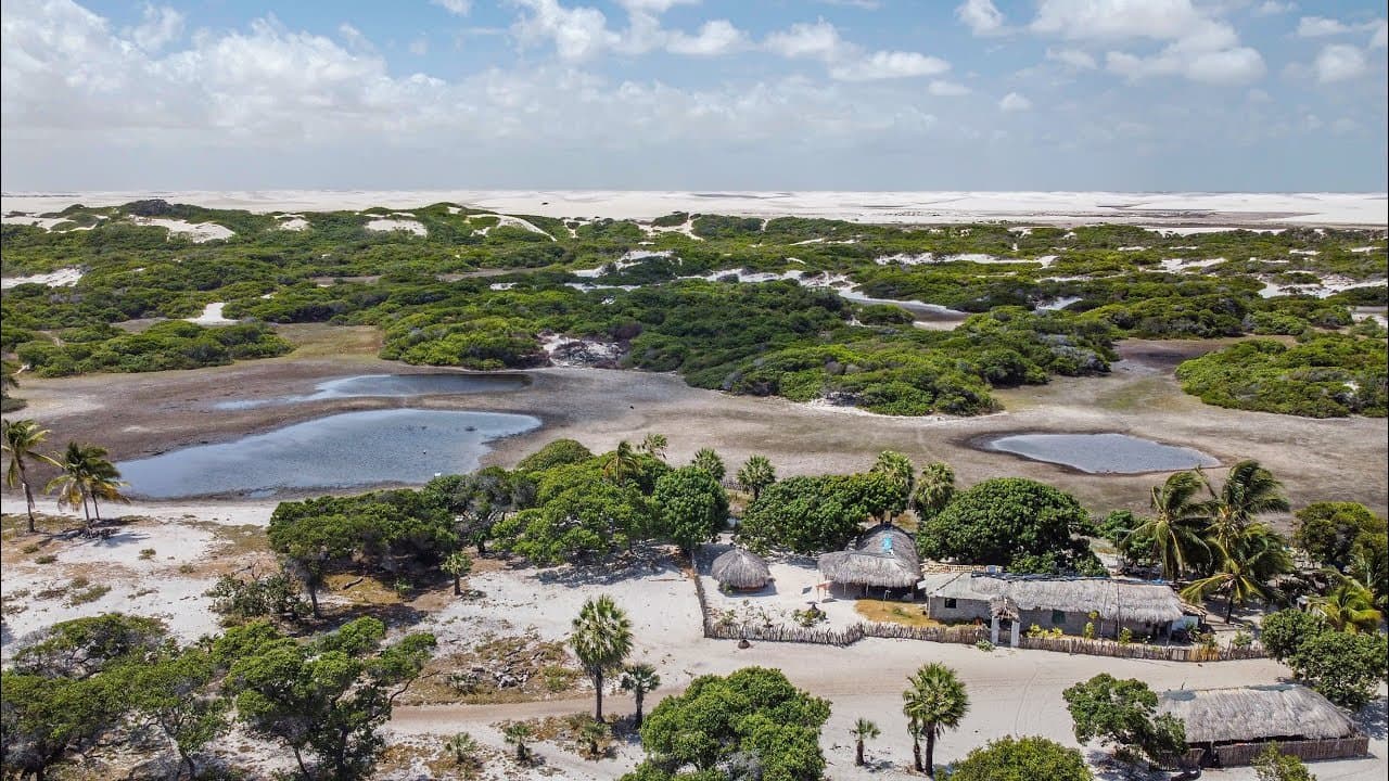 Un hameau, deux lagunes, des dunes à perte de vue. Pas besoin d'en dire plus. Vue aérienne d'un petit village aux toits de chaume niché entre des dunes de sable blanc, une végétation d'arbustes et des lagunes peu profondes sur l'itinéraire de randonnée équestre dans les Lençóis Maranhenses