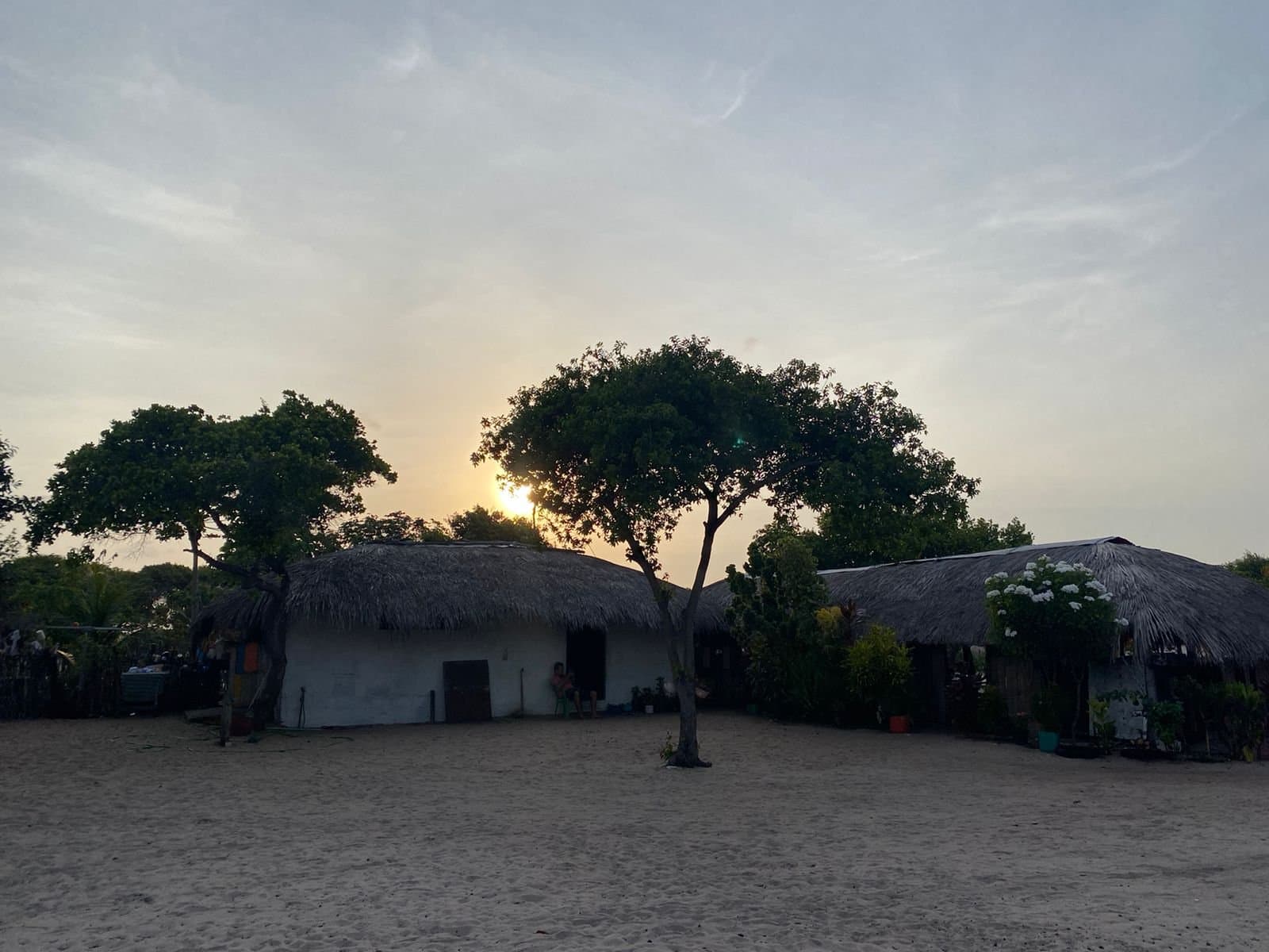 Le genre d'endroit où personne ne regarde sa montre au dîner. Maisons blanchies à la chaux avec toits de chaume et un arbre solitaire se découpant au coucher du soleil sur un sol sableux, typique des communautés locales de la randonnée à cheval dans les Lençóis Maranhenses