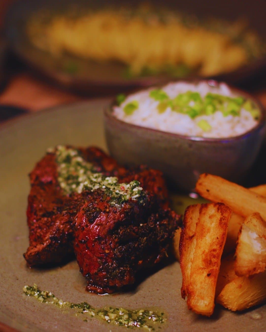 Comida de lodge boa de verdade, com gosto de rio e floresta. Filé grelhado com crosta de ervas e chimichurri, acompanhado de macaxeira frita e arroz branco com cebolinha, servido no Juma Amazon Jungle Lodge