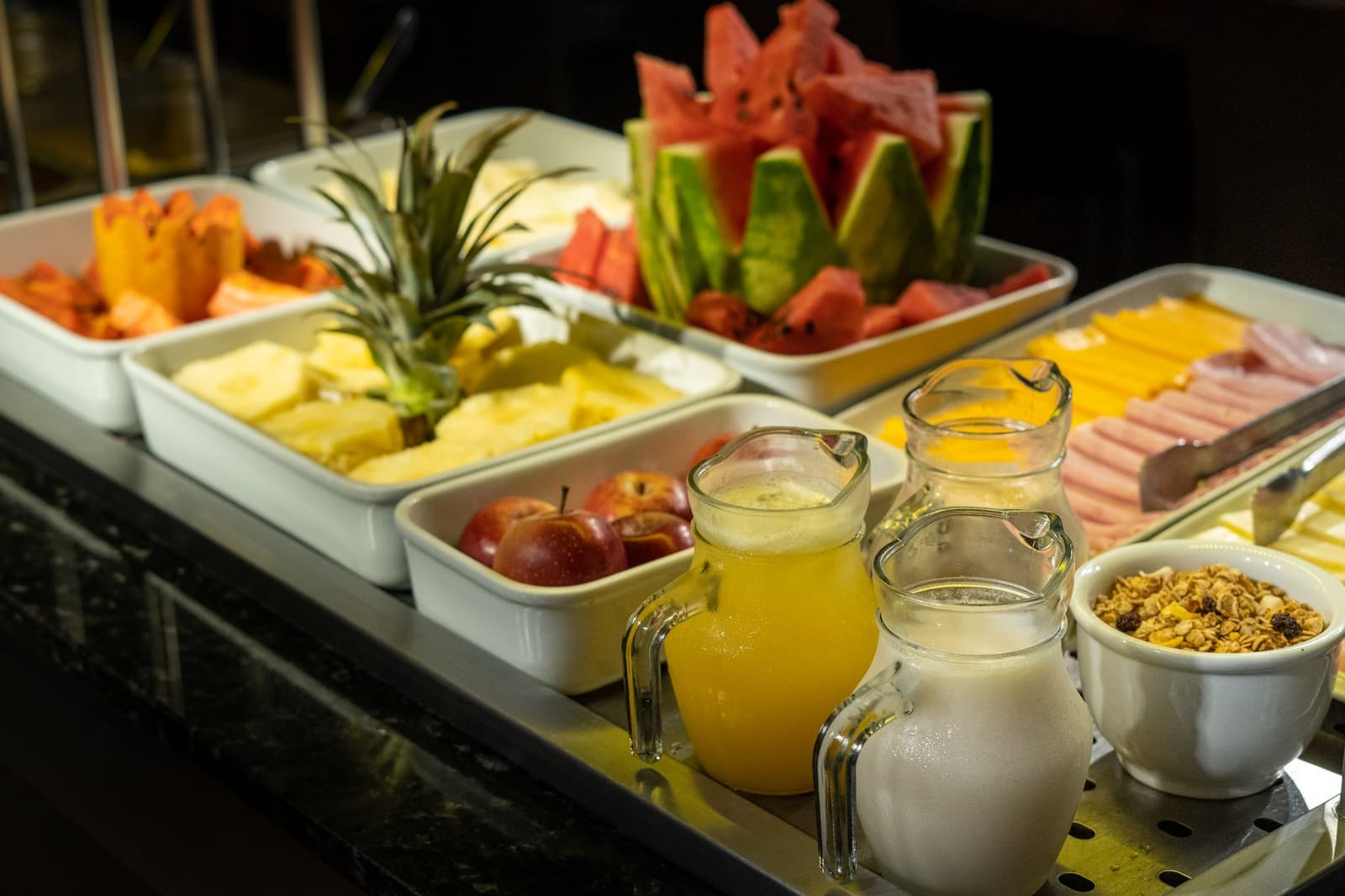Fruit at breakfast hits differently when it was growing nearby yesterday. A generous breakfast buffet aboard a luxury Amazon cruise in Brazil, featuring trays of sliced pineapple, watermelon, apples and papaya alongside pitchers of fresh juice, milk, sliced cold cuts, cheese and a bowl of granola