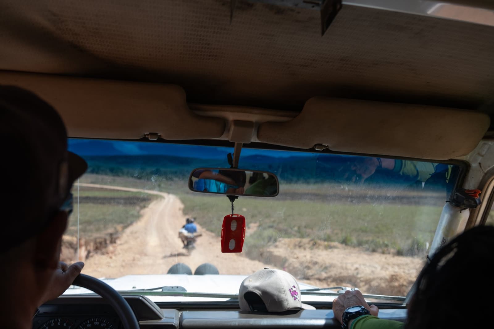 La piste commence bien avant que la montagne n'apparaisse. Vue depuis l'intérieur d'un 4x4 lors du trek du mont Roraima, suivant un motocycliste sur une piste sinueuse à travers la savane ouverte