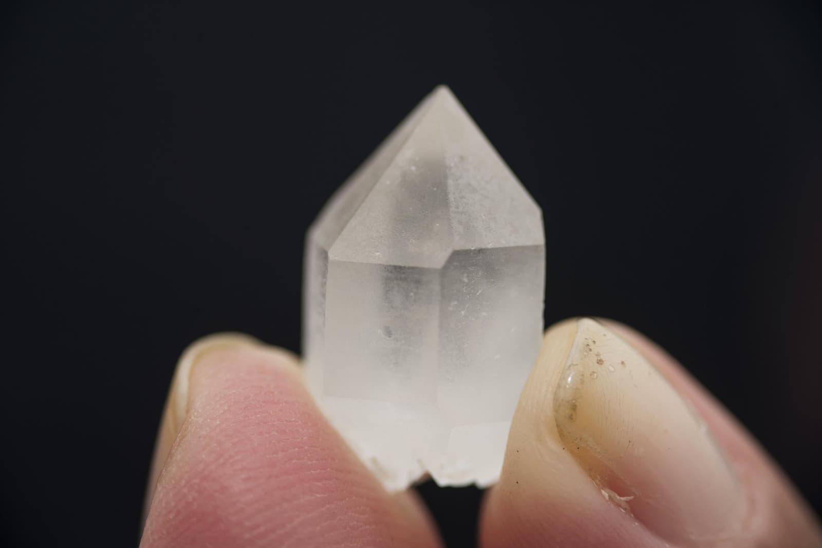 Un fragment du tepui, petit mais formé bien avant nous. Un petit cristal de quartz transparent tenu entre deux doigts sur fond noir, découvert lors du trek du mont Roraima dans la Vallée des Cristaux
