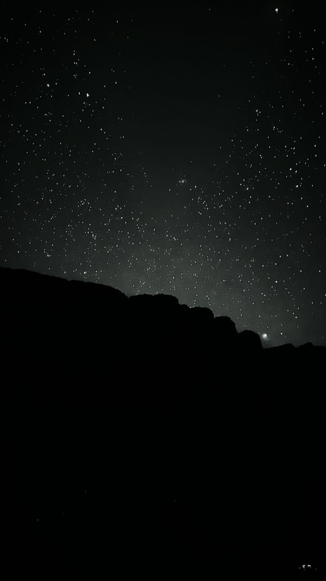 La nuit tombe, les étoiles prennent le relais. Un ciel nocturne saturé d'étoiles domine la silhouette sombre d'une crête rocheuse lors du trek du Mont Roraima