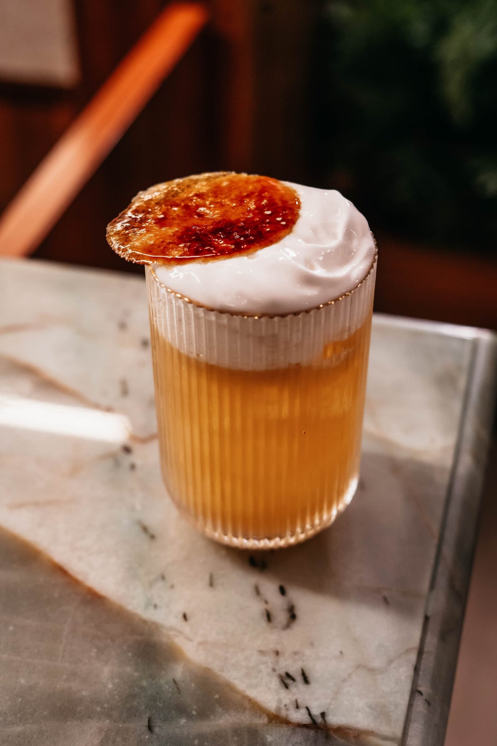 La jungle attend, mais ce verre mérite qu'on s'attarde. Un verre cannelé rempli d'un cocktail ambré, surmonté d'une mousse blanche épaisse et d'un disque caramélisé brûlé, servi à bord de l'untamed amazon cruise