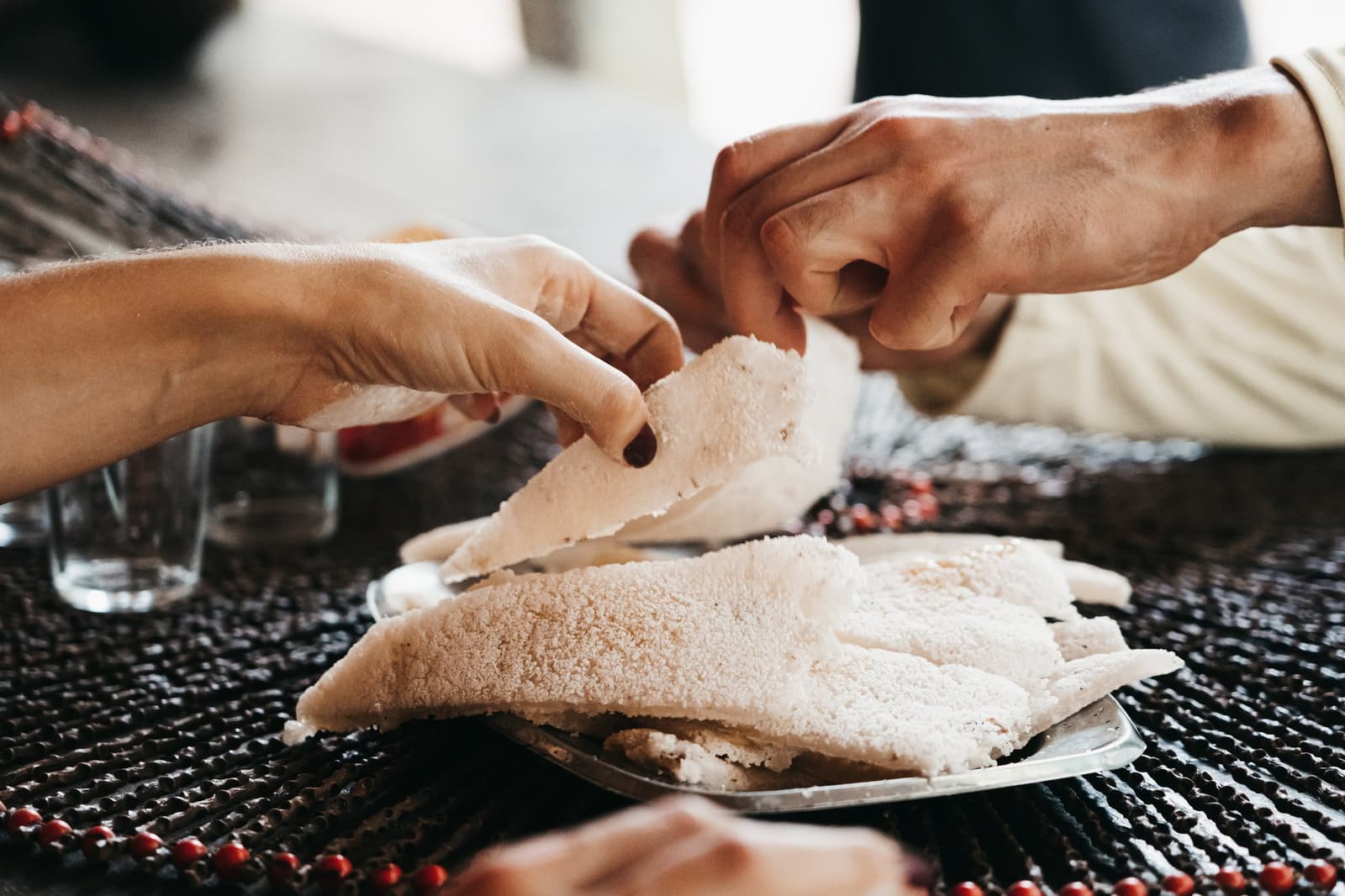 Le tapioca, ça se déchire à deux. Une évidence sur le fleuve. Deux personnes partagent un pain plat de manioc moelleux au-dessus d'une assiette commune lors d'une croisière sur l'Amazone
