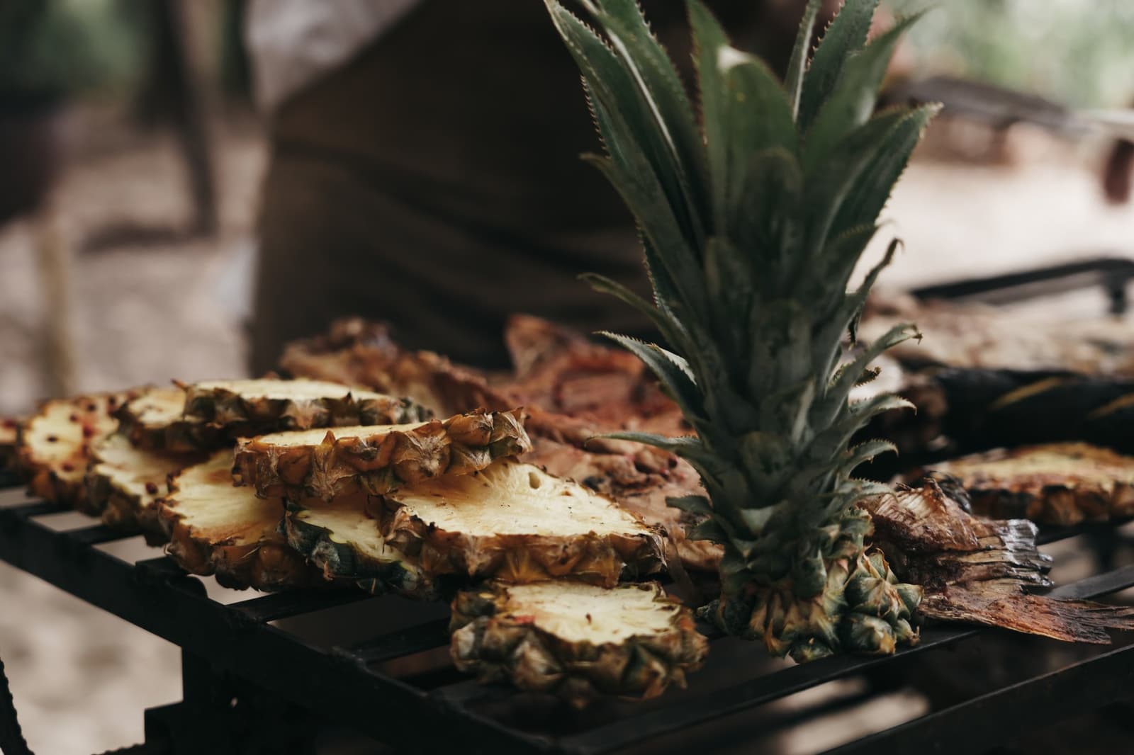 Un ananas grillé sur braise, et le repas devient une histoire à raconter. Ananas coupé en deux avec sa couronne intacte posé sur une grille de barbecue sombre, accompagné de tranches caramélisées, servi lors de l'Untamed Amazon Cruise