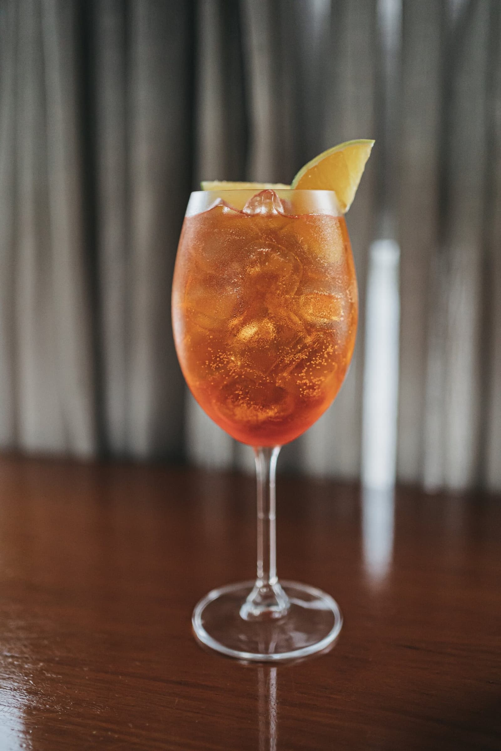 Le fleuve peut attendre, ce verre, non. Un cocktail ambré sur glace dans un verre à pied garni d'un quartier d'agrume, servi sur un bar en bois sombre à bord de l'Untamed Amazon Cruise