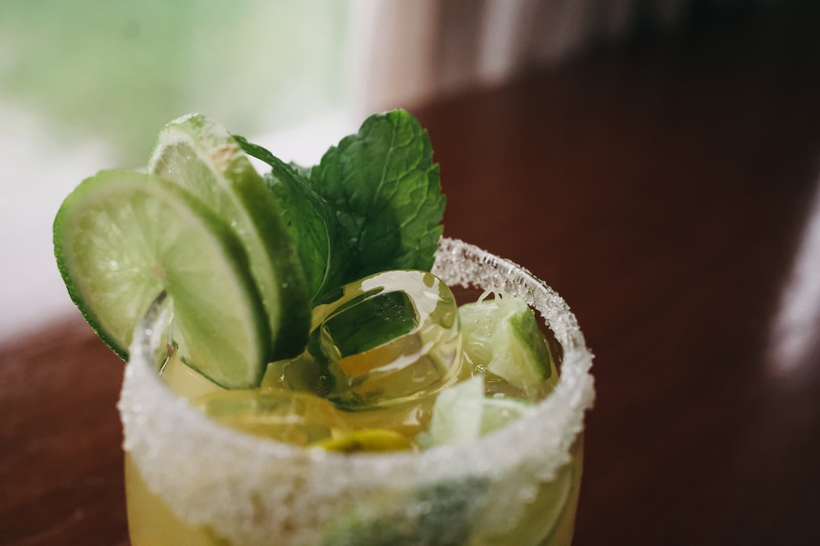 Le fleuve peut attendre, ce verre mérite toute l'attention. Un verre à bord givré de sucre, garni de tranches de concombre, de quartiers de citron vert et de feuilles de menthe fraîche