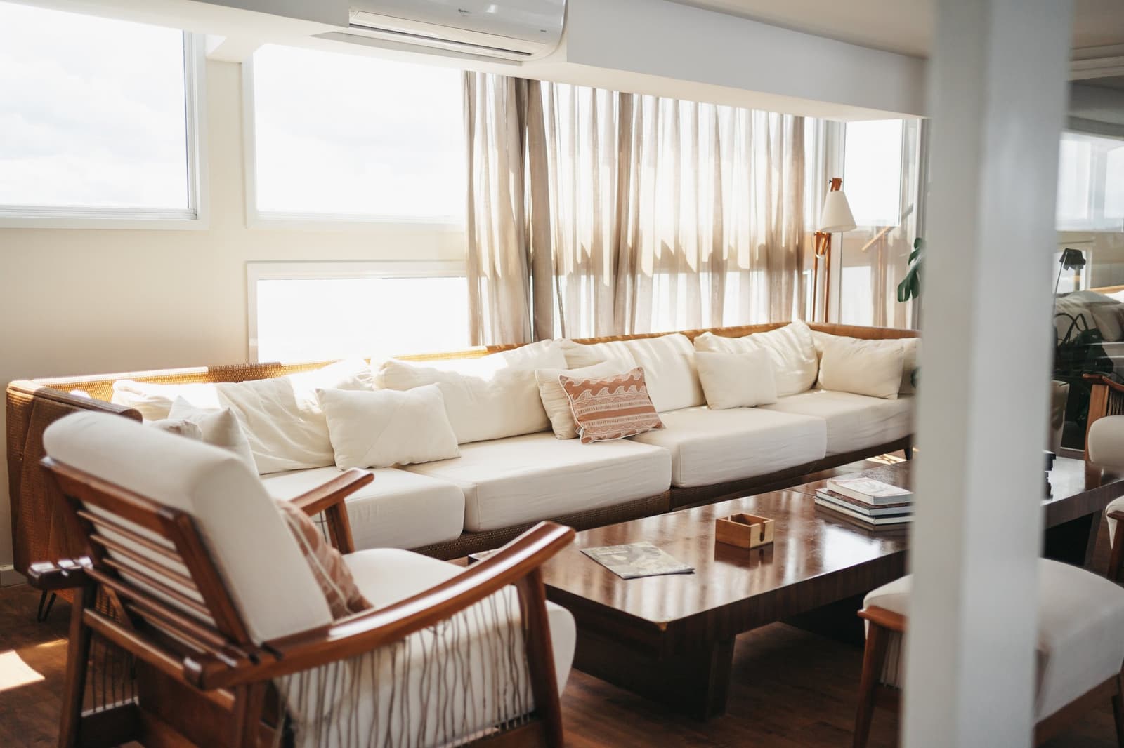 Le genre de salon où les heures passent sans qu'on les voie. Salon lumineux de l'untamed amazon cruise avec un grand canapé crème à structure en rotin, des fauteuils en bois et une table basse polie sous des rideaux en lin translucide