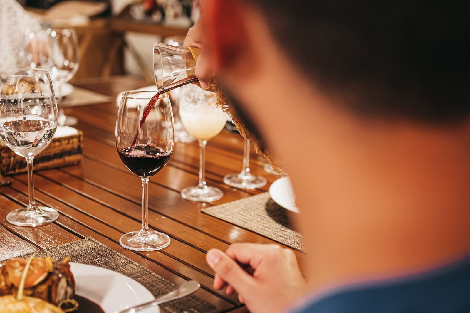 Un verre de rouge, le fleuve tout près. Les dîners à bord ont leur propre rythme. Du vin rouge versé dans un verre en cristal sur une table élégamment dressée à bord de l'untamed amazon cruise, avec des cocktails et des plats servis visibles