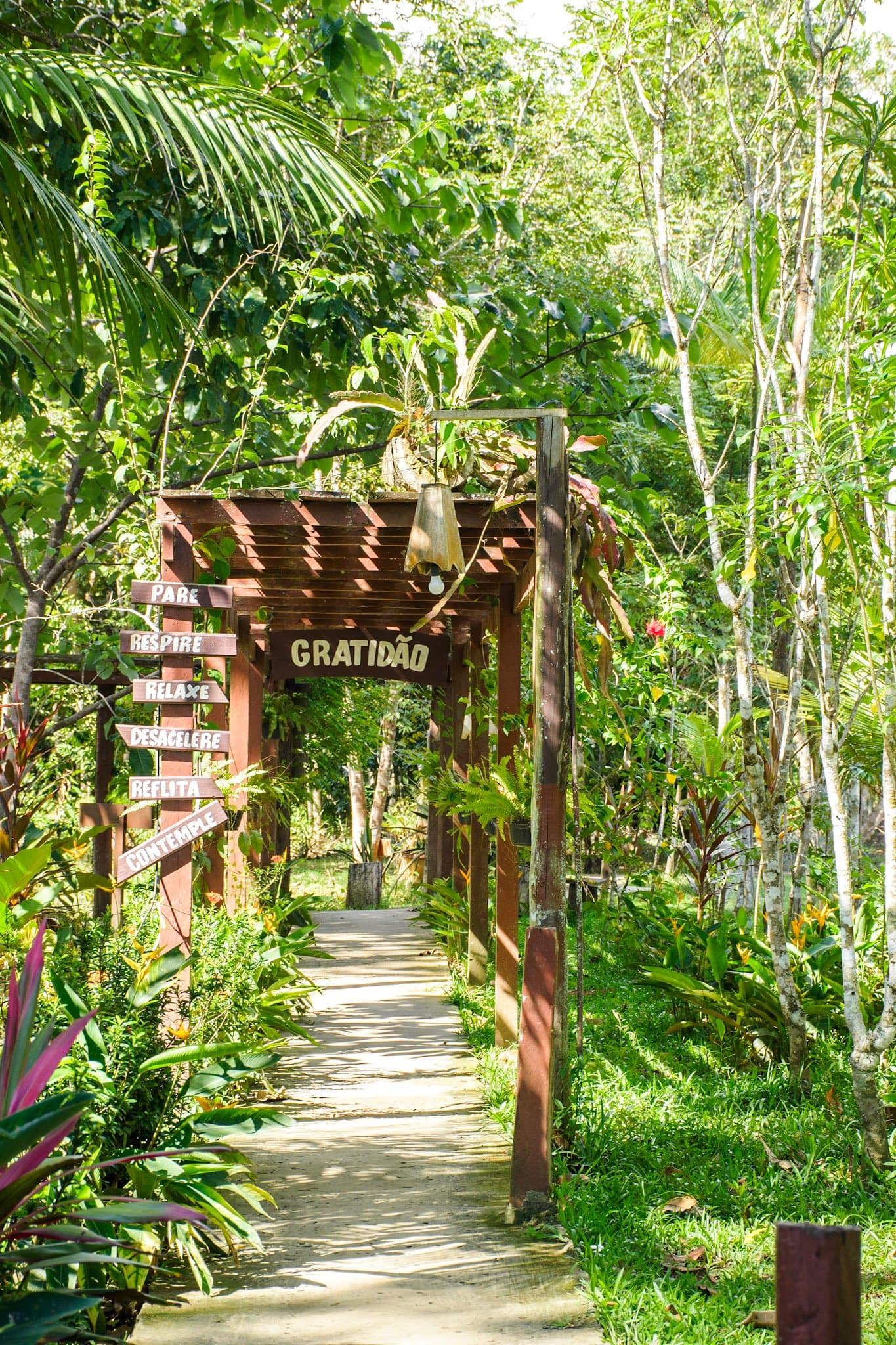 Stoppen, ademhalen, vertragen. De lodge maakt het duidelijk voor je je tas hebt uitgepakt. Een houten pergola-poort met het opschrift 'Gratidão' (Dankbaarheid) bij de ingang van een junglepad, omringd door weelderig tropisch groen en een wegwijzer met 'Pare, Respire, Relaxe, Desacelere, Reflita, Contemple'