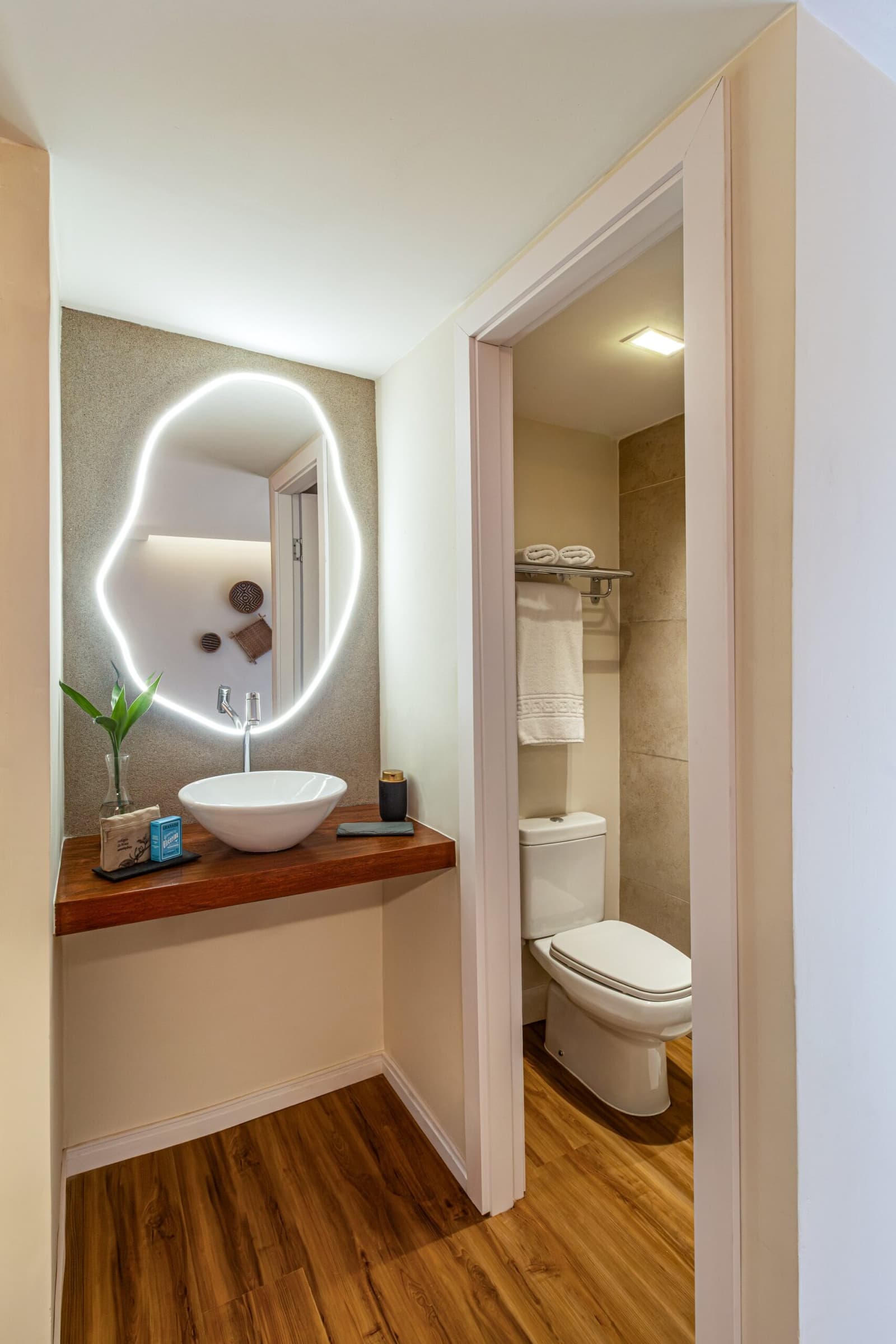 Een badkamer die je niet verwacht midden in het regenwoud. Photo: STUDIO CREATE Privébadkamer van een suite op een luxe Amazone-cruise in Brazilië, met opzetwasbak op een warm houten blad, organisch gevormde LED-verlichte spiegel en een apart toilet met opgerolde handdoeken en steenlook wandtegels