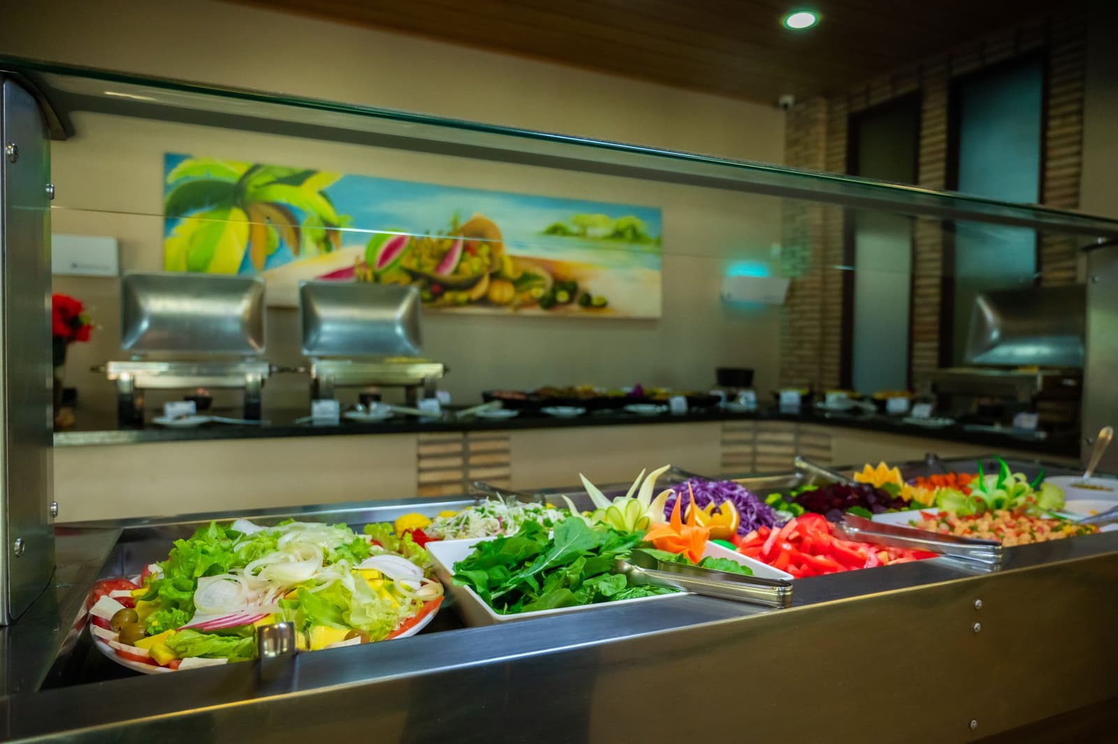 Na een dag vol wildlife weet je dit soort kleurrijke borden pas echt te waarderen. Een goed gevulde saladebuffettafel tijdens een Amazon- en Pantanal-tour, met bakken verse sla, spinazie, rode kool, gesneden tomaten en gesneden groentegarnituren achter een glazen spatscherm