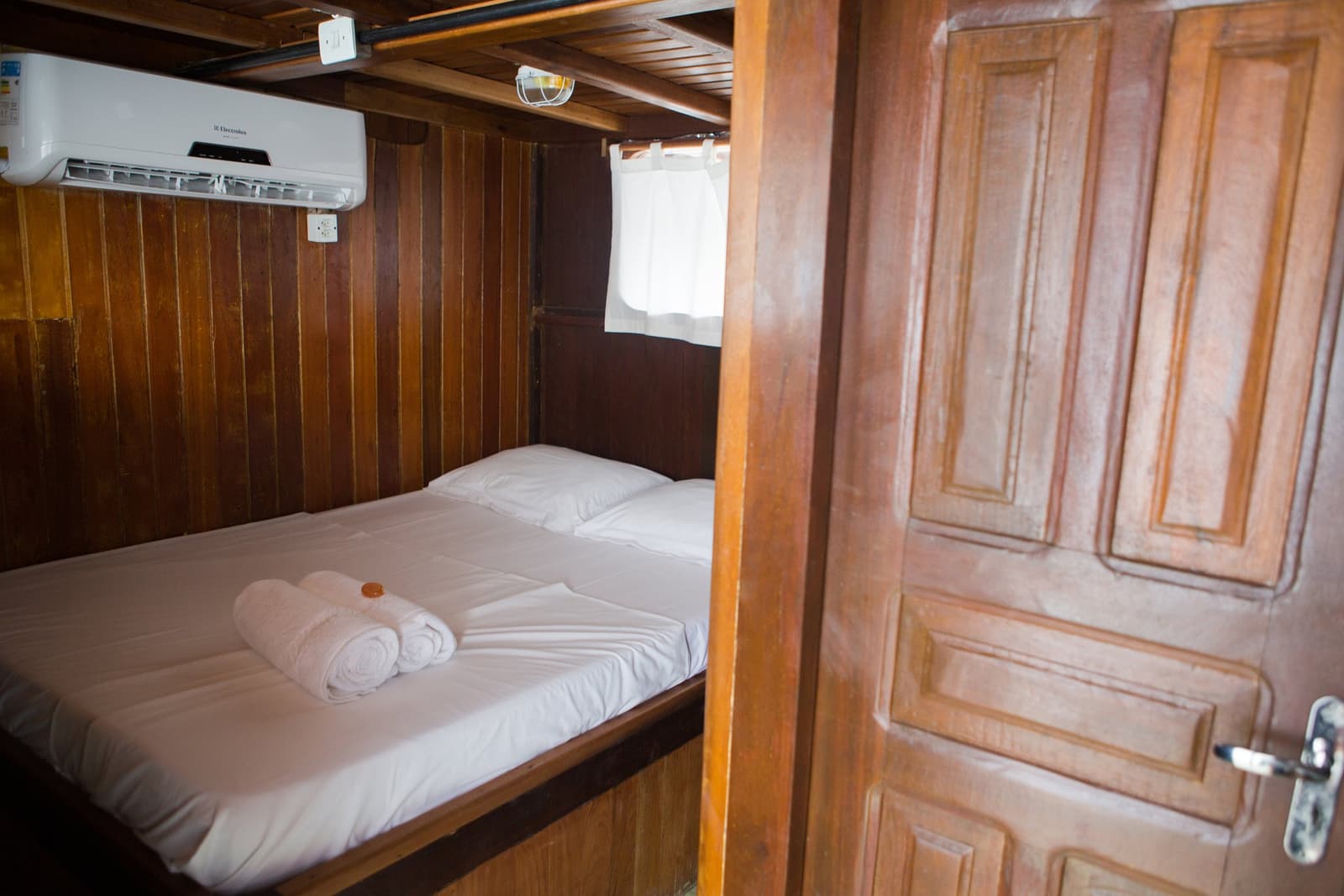 Cabine fresquinha, rio lá fora, e sono garantido depois de um dia cheio. Photo: sitah Cabine aconchegante com lambris de madeira em um cruzeiro pelo Rio Amazonas no Brasil, com cama de casal, toalhas brancas enroladas, vigia e ar-condicionado