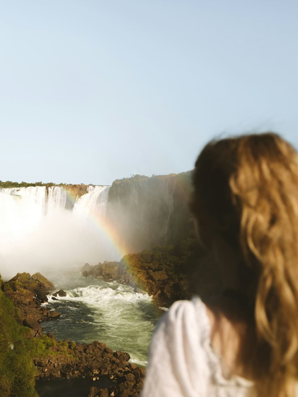 Une femme observe les chutes d'Iguazu, un arc-en-ciel se formant dans les embruns, Brésil. Une femme observe les chutes d'Iguazu, un arc-en-ciel se formant dans les embruns, Brésil.