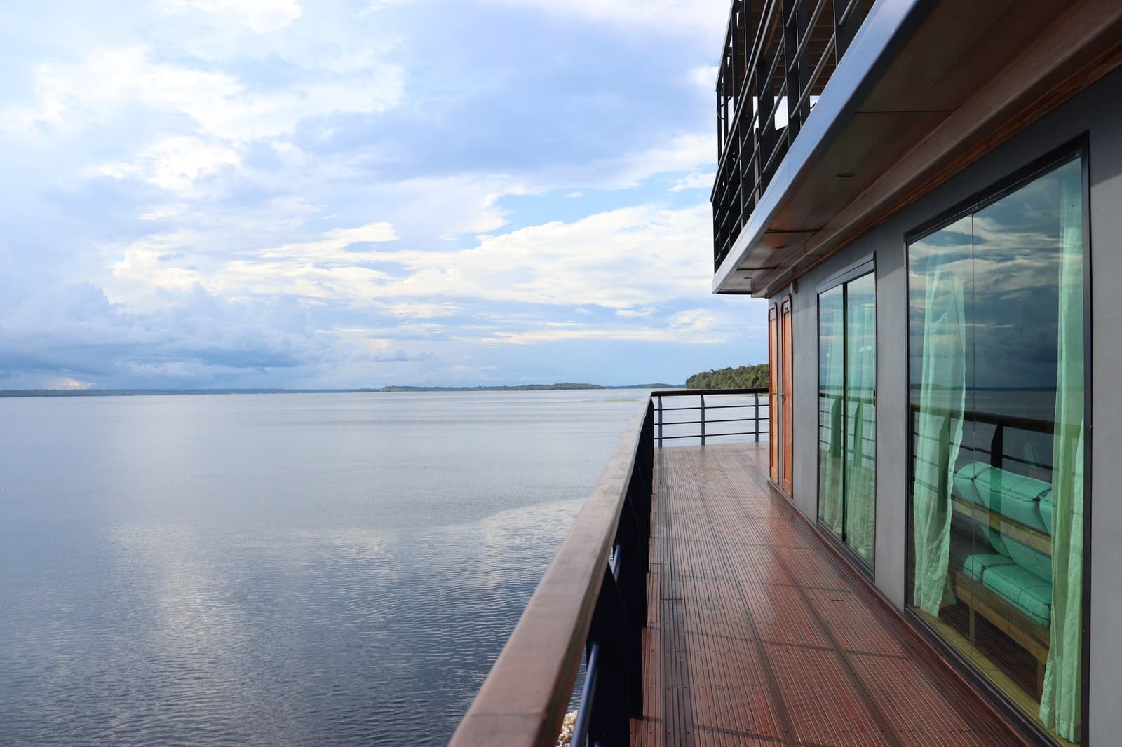 Certi panorami non chiedono altro che uno sguardo. Il ponte laterale in teak della crociera La Jangada sull'Amazzonia si estende lungo grandi vetrate delle cabine affacciate su un fiume largo e calmo con un'isola boscosa all'orizzonte