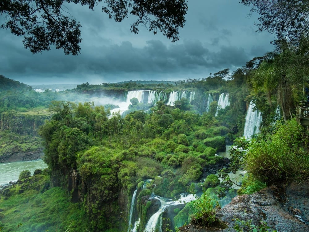 Chutes d'Iguazu vues d'un belvédère dans la forêt, sous les gros nuages d'orage de la saison des pluies, Brésil. Chutes d'Iguazu vues d'un belvédère dans la forêt, sous les gros nuages d'orage de la saison des pluies, Brésil.