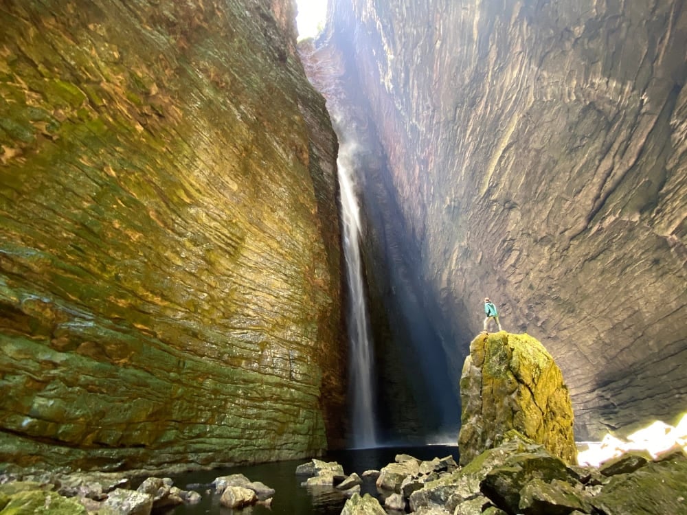 Un escursionista in piedi su un masso davanti alla cascata Fumacinha, dentro un canyon coperto di muschio nella Chapada Diamantina, in Brasile. Un escursionista in piedi su un masso davanti alla cascata Fumacinha, dentro un canyon coperto di muschio nella Chapada Diamantina, in Brasile.